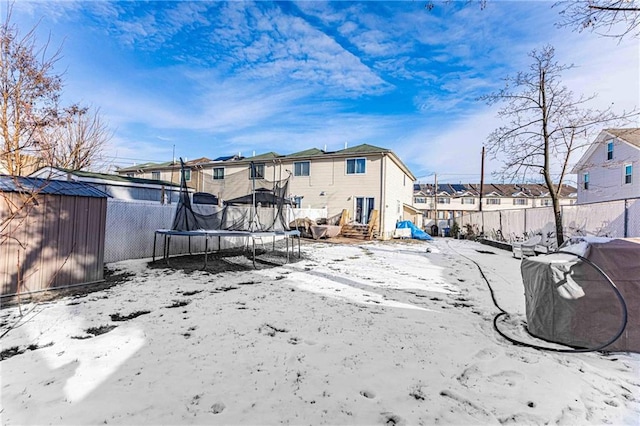 yard covered in snow featuring a trampoline and a storage unit