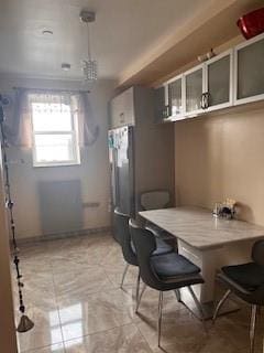 kitchen with a kitchen bar, light tile patterned floors, glass insert cabinets, and freestanding refrigerator