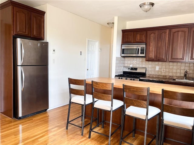 680 81st St Unit 3B, Brooklyn, NY 11228 - kitchen featuring stainless steel appliances, butcher block countertops, a sink, decorative backsplash, and a kitchen breakfast bar