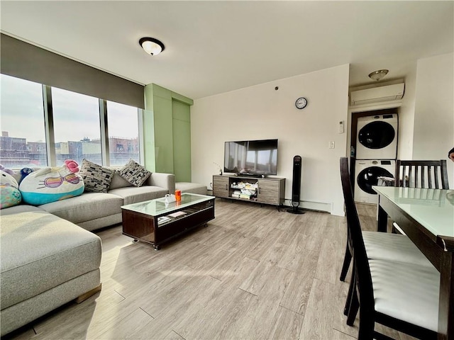 living room featuring a wall mounted air conditioner, light wood-type flooring, baseboard heating, and stacked washing maching and dryer