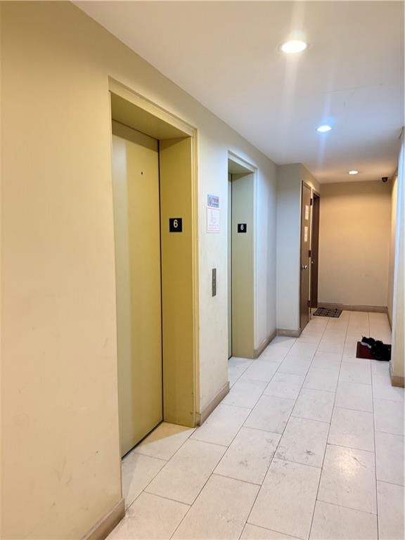 hall featuring light tile patterned floors and elevator