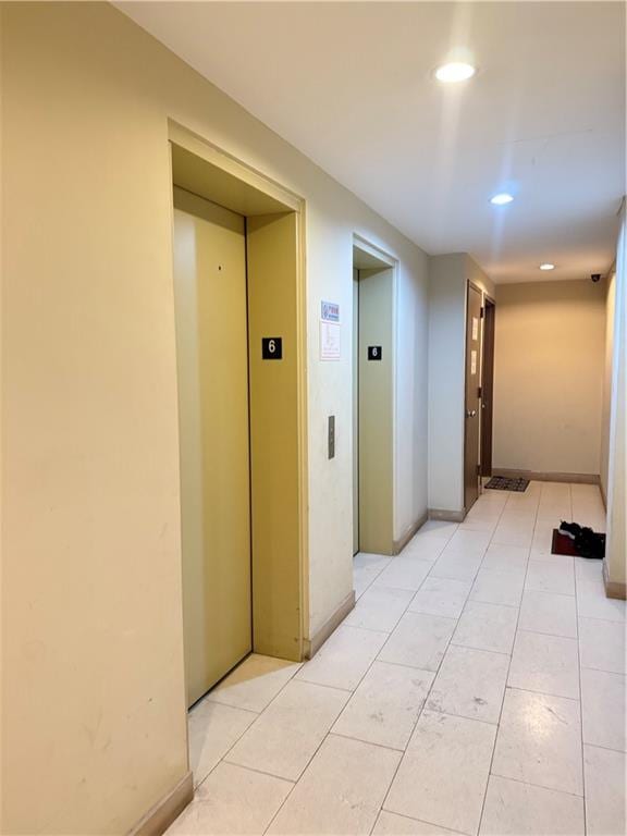 hallway featuring baseboards, elevator, recessed lighting, and light tile patterned floors