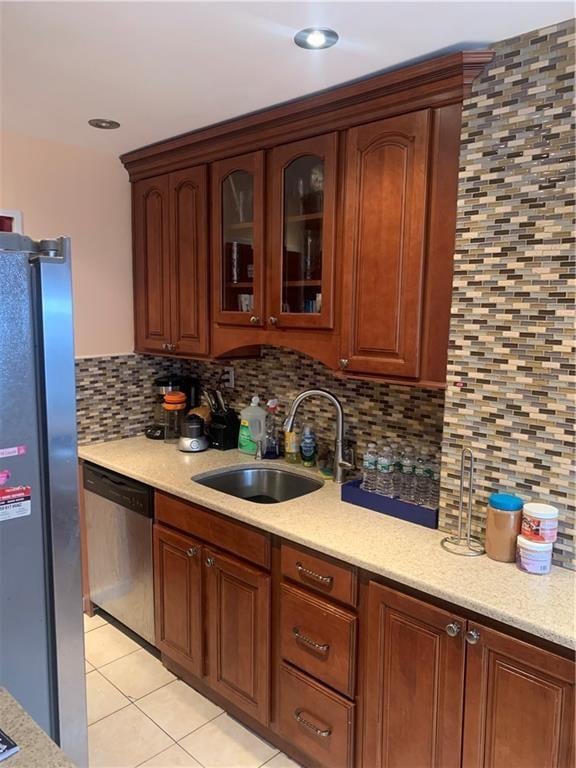 kitchen featuring appliances with stainless steel finishes, sink, light tile patterned floors, and backsplash