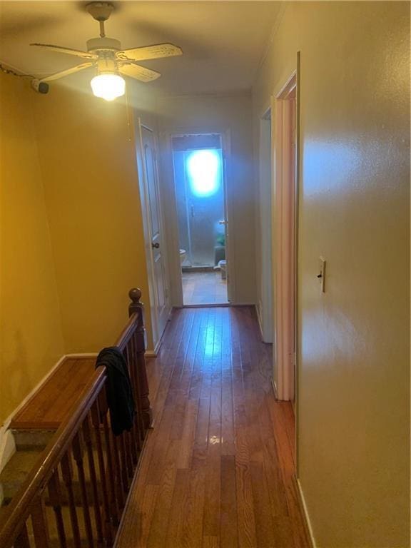 corridor with wood finished floors and an upstairs landing