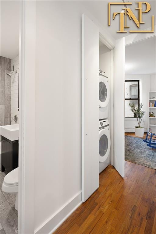 washroom featuring wood finished floors, laundry area, and stacked washing maching and dryer