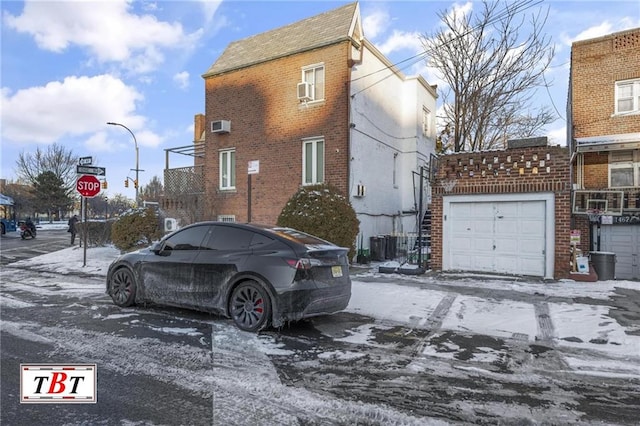 snow covered property featuring a garage and brick siding