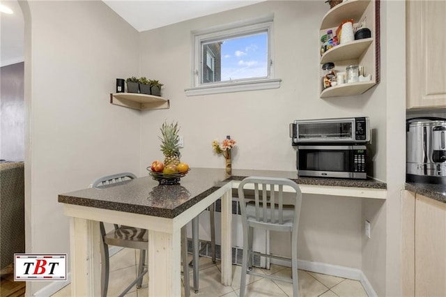 interior space featuring dark countertops, a toaster, tile patterned floors, stainless steel microwave, and baseboards