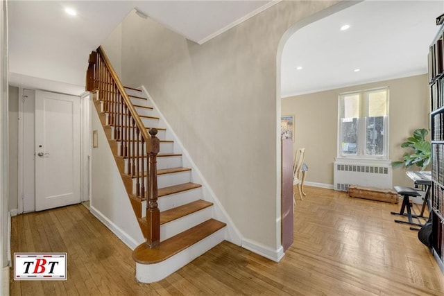 stairs with arched walkways, recessed lighting, baseboards, radiator, and crown molding