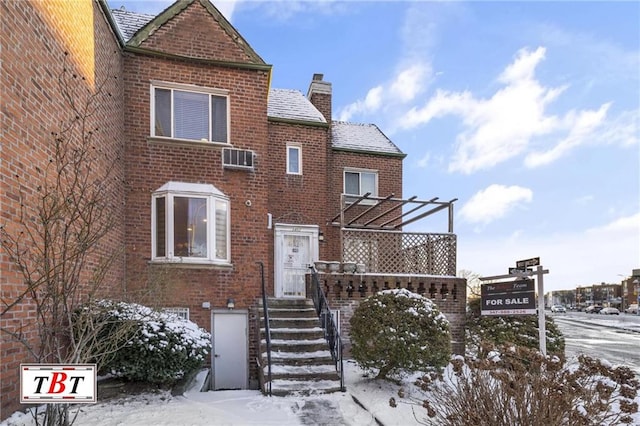 view of front facade featuring brick siding and a chimney