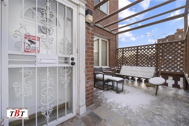 view of exterior entry featuring a pergola, a patio area, and brick siding