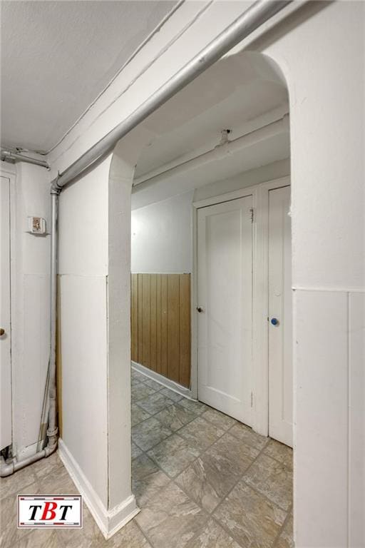 hall with arched walkways, wooden walls, and a wainscoted wall
