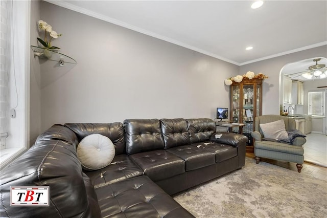 living area featuring wood finished floors, recessed lighting, crown molding, ceiling fan, and arched walkways