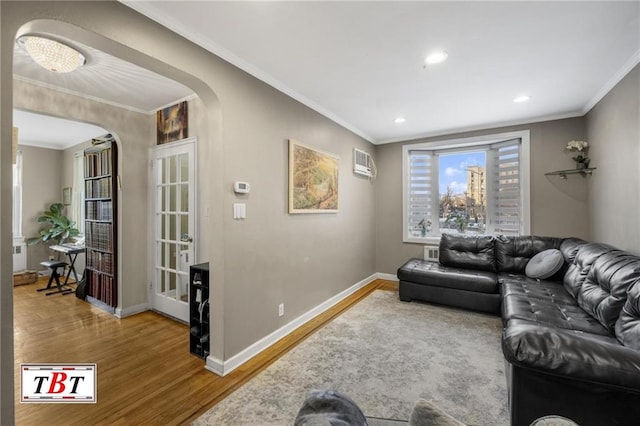 living room with crown molding, arched walkways, an AC wall unit, and wood finished floors