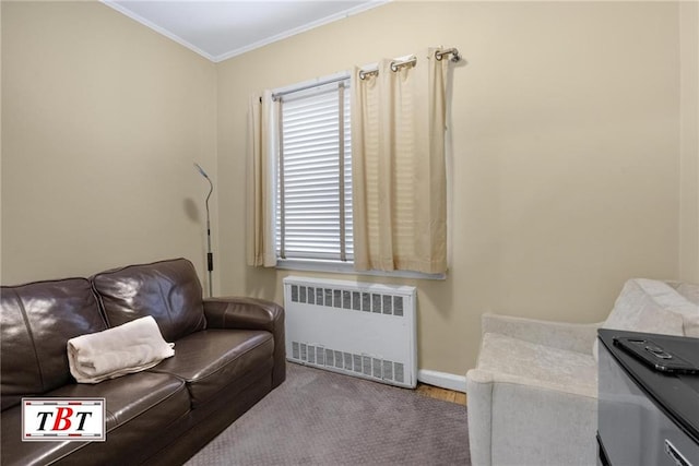 sitting room with radiator, wood finished floors, baseboards, and ornamental molding