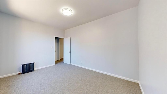 carpeted empty room with baseboards and radiator