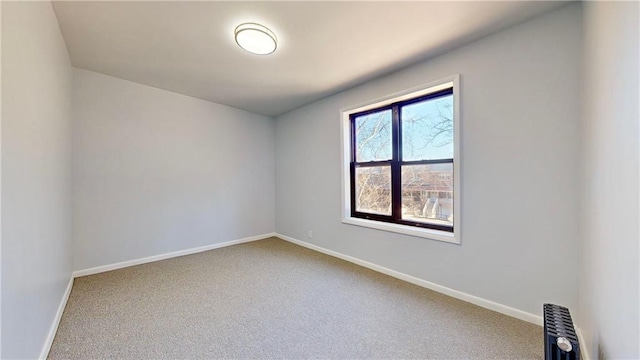 carpeted spare room with baseboards and radiator