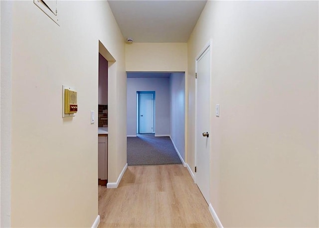 corridor featuring baseboards and light wood-style floors
