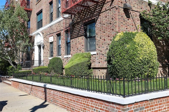 view of side of home with brick siding and fence
