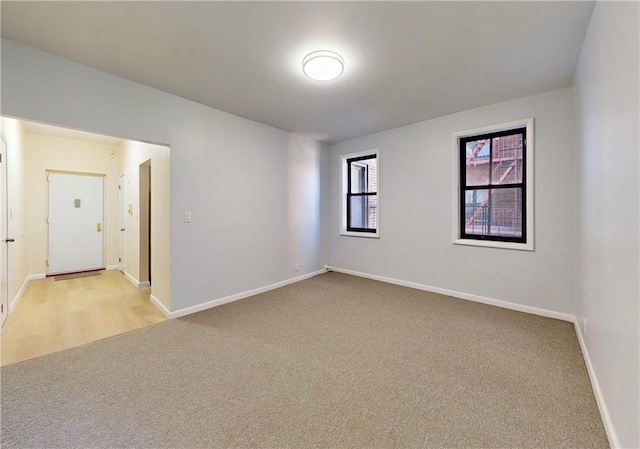 spare room featuring baseboards and light carpet