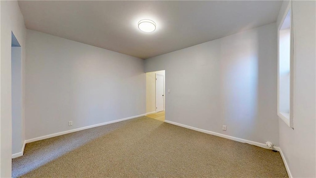 carpeted spare room featuring baseboards