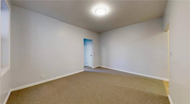 spare room with baseboards and carpet