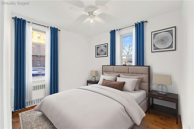 unfurnished room with ceiling fan, radiator heating unit, and wood-type flooring