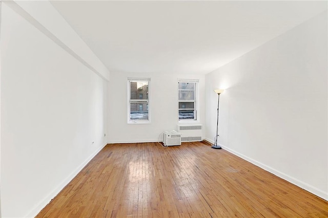 spare room with radiator, light wood-style flooring, and baseboards