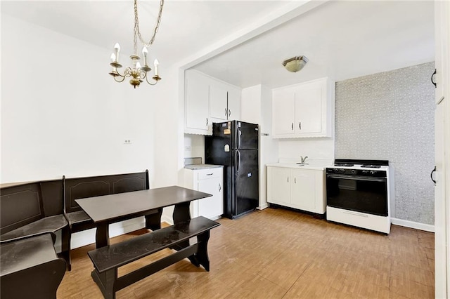 kitchen featuring black fridge, decorative light fixtures, gas range oven, and white cabinets