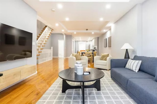 living room with hardwood / wood-style flooring and a tray ceiling