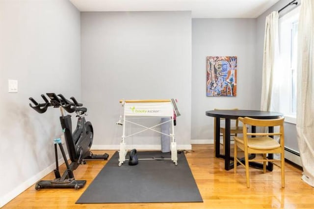 workout room featuring hardwood / wood-style flooring and baseboard heating