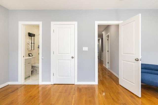 unfurnished bedroom featuring hardwood / wood-style floors and connected bathroom