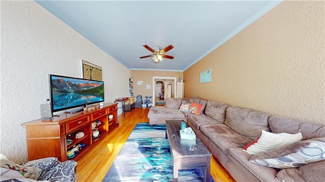 living room with hardwood / wood-style flooring, ornamental molding, and ceiling fan