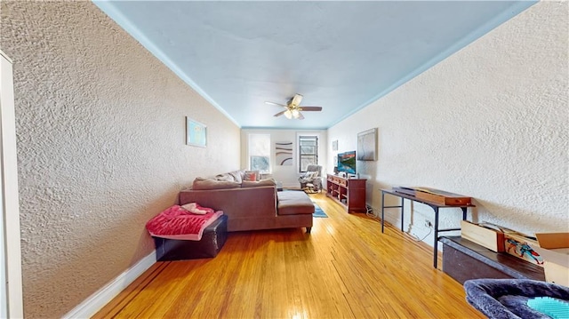 living room with hardwood / wood-style flooring, ornamental molding, and ceiling fan