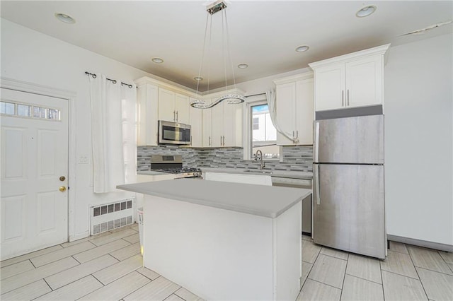 kitchen with sink, a center island, hanging light fixtures, stainless steel appliances, and white cabinets