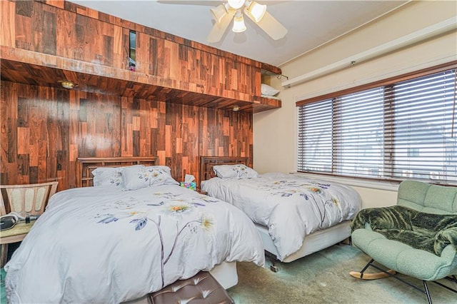 bedroom with ceiling fan, carpet floors, and wood walls