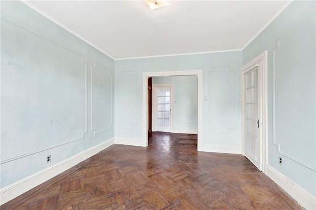 spare room with baseboards, ornamental molding, and a decorative wall