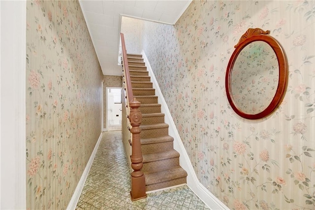 staircase featuring wallpapered walls and baseboards