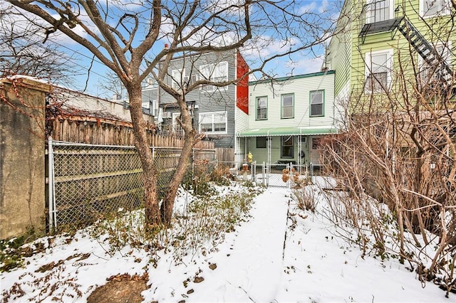 snow covered house with a gate and a fenced front yard