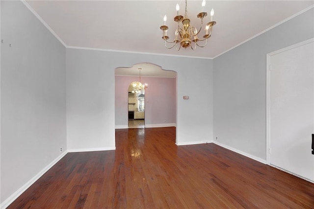 empty room featuring arched walkways, dark wood finished floors, a notable chandelier, ornamental molding, and baseboards