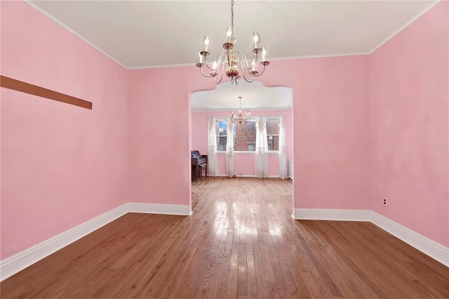 unfurnished dining area featuring ornamental molding, a notable chandelier, hardwood / wood-style floors, and baseboards