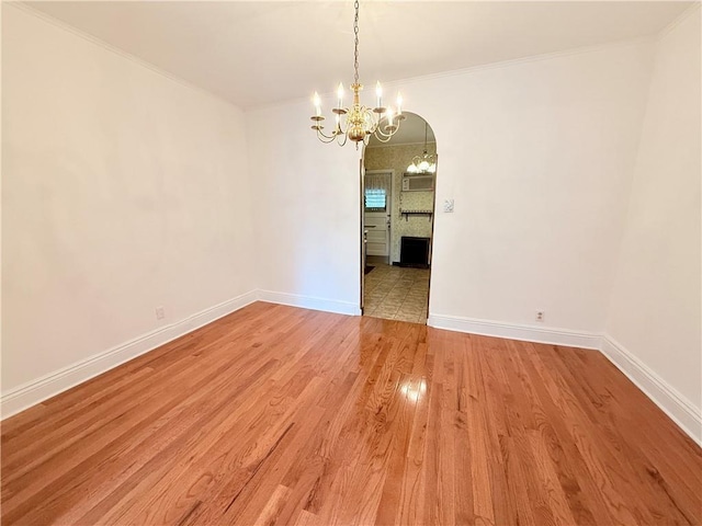 552 17th St, Brooklyn, NY 11215 - spare room with a chandelier, baseboards, light wood-style flooring, ornamental molding, and arched walkways
