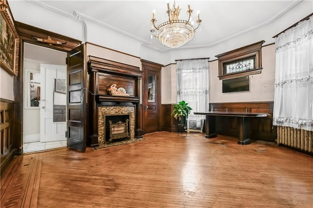 515 E 24th St, Brooklyn, NY 11210 - unfurnished living room with wood-type flooring, a chandelier, crown molding, a fireplace with flush hearth, and a wainscoted wall