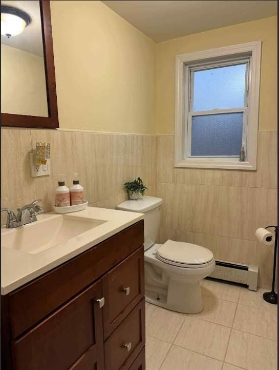 bathroom featuring tile walls, vanity, baseboard heating, toilet, and tile patterned floors