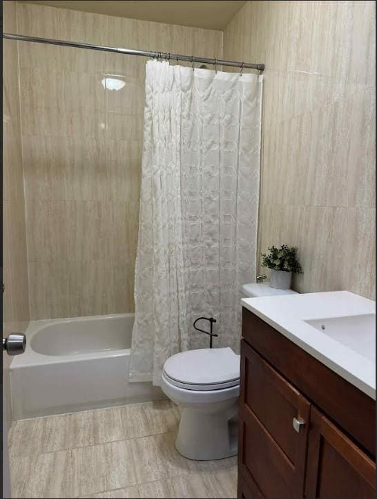 full bathroom with vanity, toilet, tile walls, and shower / bath combo