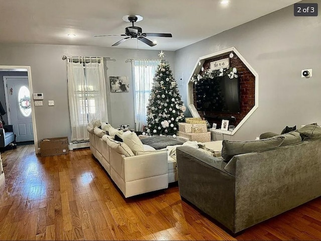 living room with wood-type flooring, ceiling fan, and baseboard heating