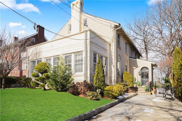 view of side of home featuring stucco siding and a yard