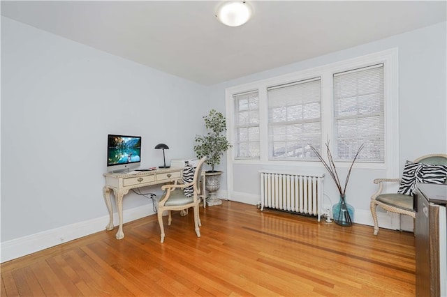 office space featuring baseboards, light wood-style flooring, and radiator heating unit