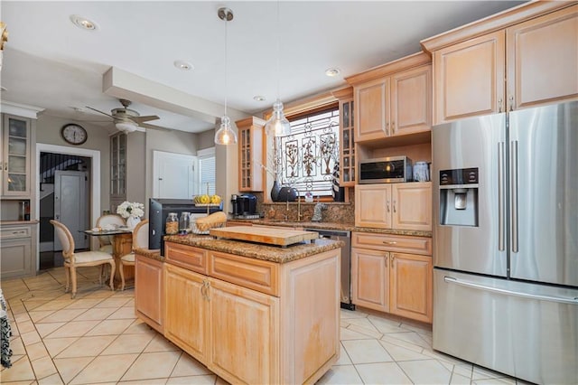 kitchen with light tile patterned flooring, a kitchen island, light brown cabinets, and stainless steel appliances