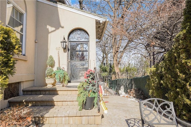 property entrance with fence and stucco siding