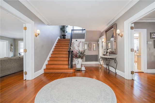 entrance foyer with wood finished floors, stairs, and crown molding